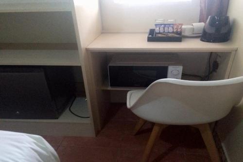 a room with a desk with a microwave and a chair at Maluti Backpackers in Phuthaditjhaba
