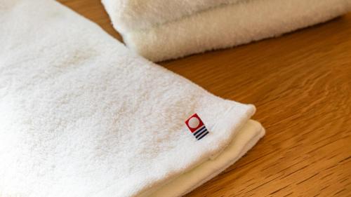 a white towel with a red cross on it at ESPLANADE VILLAGE HOTEL b in Kamakura