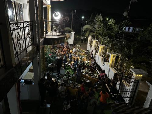 a group of people sitting at tables in a courtyard at night at MICASO Guest House in Limbe