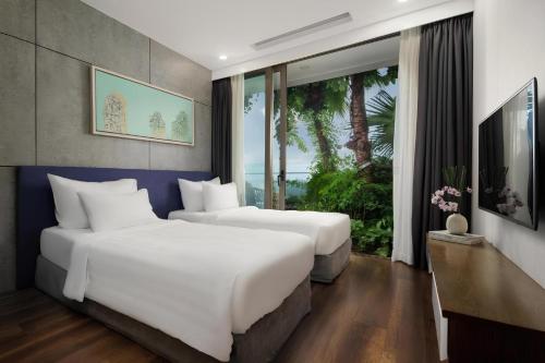 two beds in a hotel room with a large window at Flamingo Resort Dai Lai in Ngọc Quang