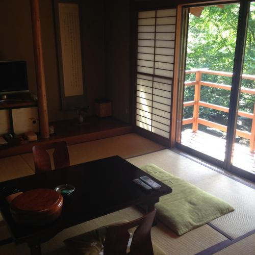 a dining room with a table and a door to a balcony at 中棚荘 in Komoro