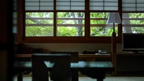 a room with a desk with a computer and two windows at 中棚荘 in Komoro