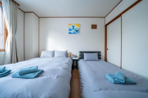 two beds in a small room with blue pillows at Yadokito 1 in Otaru