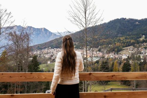 a woman standing on a balcony looking out at a city at Camping Essenza Alpina in Folgaria