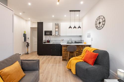 un salon avec un canapé et une cuisine dans l'établissement Cozy & Central Fully Equipped Studio 5 min walk to metro, Montparnasse neighbourhood, à Paris
