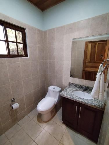 a bathroom with a toilet and a sink and a mirror at Bungalows Beachfront Hotel in Punta Uva