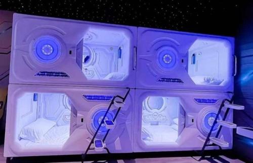a room with four beds in it with purple lighting at bambu hostel capsules in Seville
