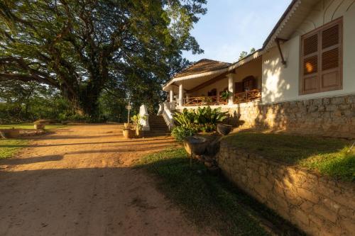 a house with a stone wall next to a yard at Clodagh Manor House by Seven Angels in Matale