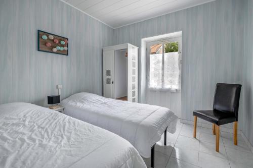 a bedroom with two beds and a chair and a window at Plage à 200m, maison mitoyenne de plain-pied, 4 pers in La Bernerie-en-Retz