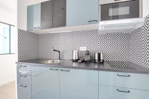 une cuisine blanche avec un évier et un micro-ondes dans l'établissement Promenade Best Bakeries from a Cozy Boho 1 Bedroom, à Paris