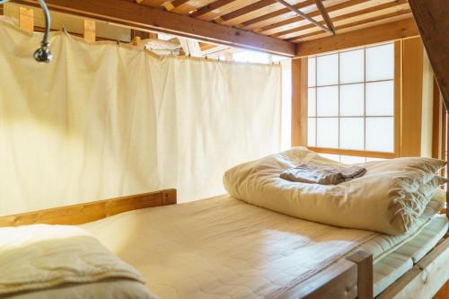 瀬戸市にあるMasukichi -hostel,cafe,souvenir,guide-の大きな窓付きの客室のベッド1台分です。