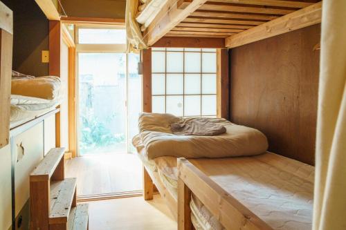 瀬戸市にあるMasukichi -hostel,cafe,souvenir,guide-の大きな窓とベッドが備わる客室です。