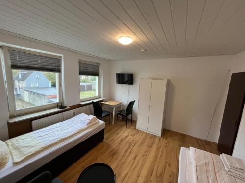 a room with two beds and a desk and a refrigerator at Monteurwohnungen nähe Holsten Galerie in Neumünster