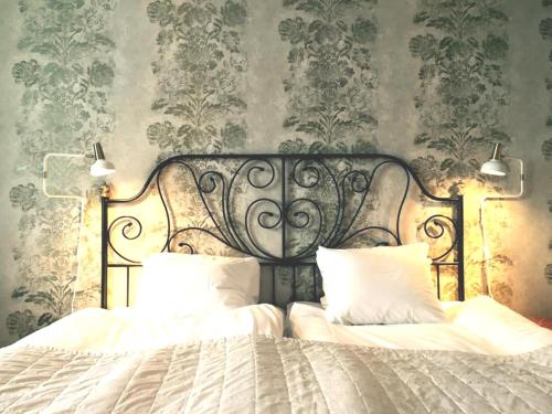 a bedroom with a bed with white sheets and wallpaper at Hotell Park in Västervik