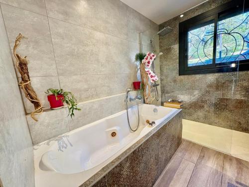 une salle de bain avec une baignoire et une fenêtre dans l'établissement La Caline, villa familiale au calme avec piscine, à Saint-Paul-en-Forêt