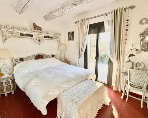une chambre avec un grand lit blanc et une fenêtre dans l'établissement La Caline, villa familiale au calme avec piscine, à Saint-Paul-en-Forêt