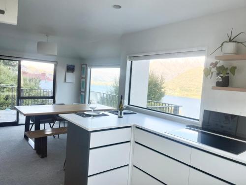 a kitchen with white cabinets and a large window at Spectacular Lake and Mountain Views Close to town in Queenstown
