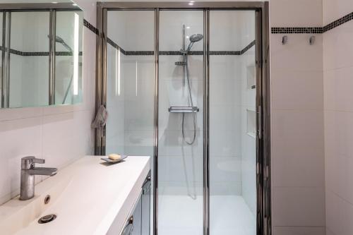 La salle de bains est pourvue d'une douche et d'un lavabo blanc. dans l'établissement Cyril - Appt au coeur du 15eme arrondissement, à Paris
