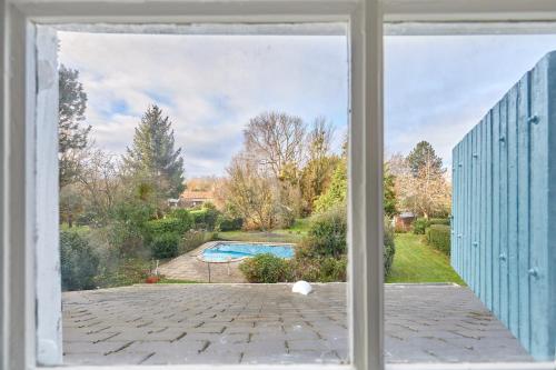 - une fenêtre offrant une vue sur la piscine dans l'établissement La Picane - Belle maison avec piscine et jardin, à Tourgéville