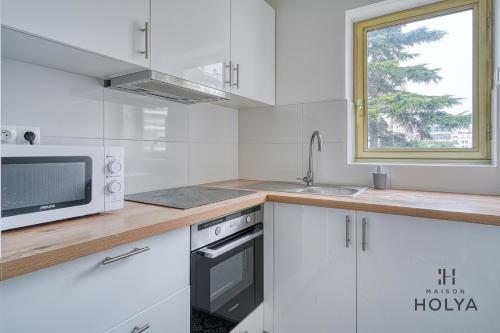 - une cuisine blanche avec un four micro-ondes et un évier dans l'établissement Le Grandiose - Aux portes de Paris - 328B, à Levallois-Perret