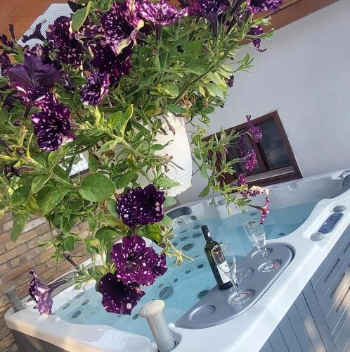 a bath tub with a vase filled with purple flowers at Szent Anna Vendégház Makó in Makó
