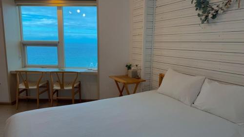 a bedroom with a bed and a table and a window at Jeju Stay Haven in Jeju