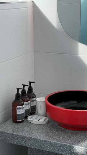 three bottles of soap and a red bowl on a counter at Jeju Stay Haven in Jeju