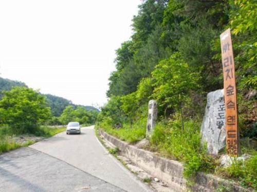 a car driving down a road with a sign at Wonju Sarichi Land in Forest Pension in Wonju