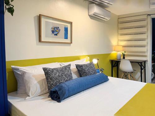 a bedroom with a bed with white and blue pillows at Cozy Condo with Balcony near Ayala Center Cebu in Cebu City