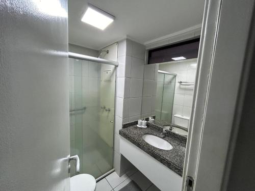 a bathroom with a sink and a glass shower at Flat de Frente para o Mar in Natal