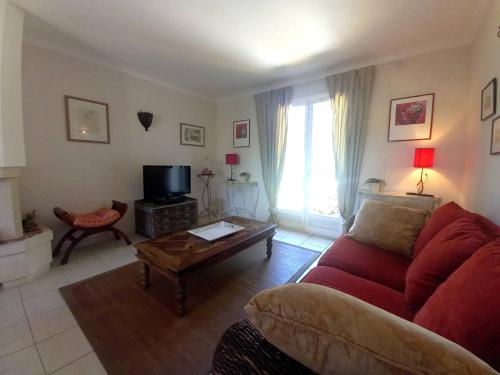 un salon avec un canapé rouge et une table dans l'établissement Saint Palais sur Mer - MAISON PROCHE LAC - 5 min à pied du SUPERMARCHE, à La Palud