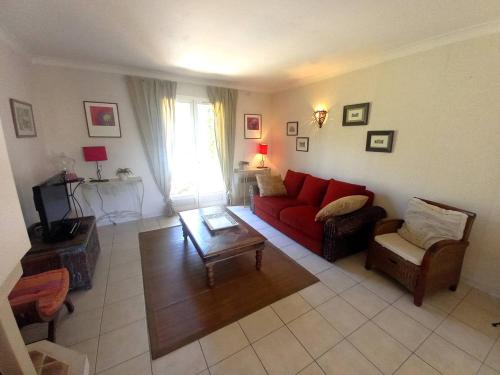 un salon avec un canapé rouge et une table dans l'établissement Saint Palais sur Mer - MAISON PROCHE LAC - 5 min à pied du SUPERMARCHE, à La Palud