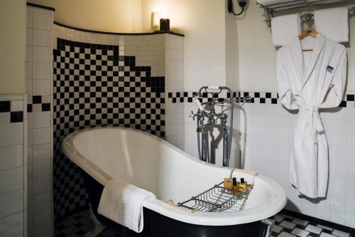 a bath tub in a bathroom with a robe on the wall at The American Colony Hotel - Small Luxury Hotels of the World in Jerusalem