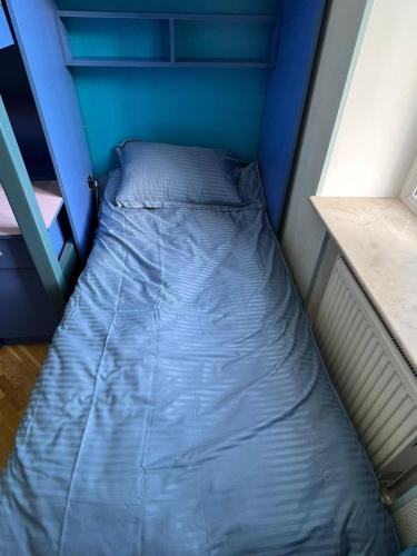 a small bed in a room with a blue wall at Cozy apartment in the heart of Baku in Baku