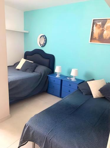 a blue bedroom with two beds and blue walls at Casa Giulù- in Palermo