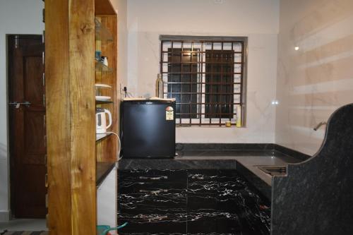 a kitchen with a black counter and a window at Vill Brahmi Stay Gokarna in Gokarn