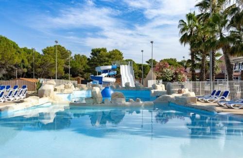 - une piscine avec des chaises et un toboggan dans l'établissement MOBIL-HOME, 6 pers, 3 ch, 2 sdb, oasis village 5 ÉTOILES, à Puget-sur Argens