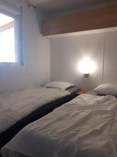 deux lits dans une chambre blanche avec une fenêtre dans l'établissement MOBIL-HOME, 6 pers, 3 ch, 2 sdb, oasis village 5 ÉTOILES, à Puget-sur Argens