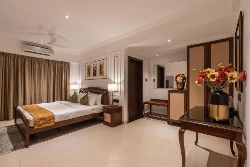 a bedroom with a bed and a vase of flowers at The Grand Central in Dona Paula