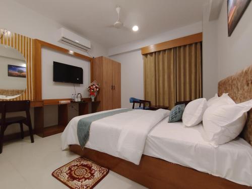 a bedroom with a bed and a desk and a television at Sylhet Paradise Inn in Sylhet