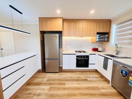 a kitchen with white cabinets and a stainless steel refrigerator at Lovely home, 3 bedrooms 4 beds, Close to hospital in Hamilton