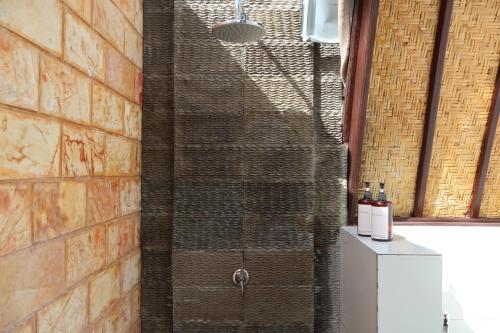 a shower in a bathroom with a brick wall at Rumah Gemala Gili Air in Gili Air