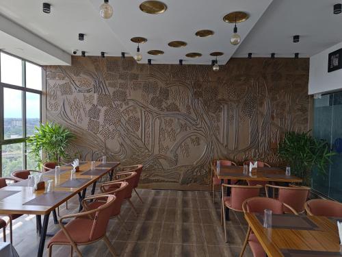 a restaurant with tables and chairs and a wall with a mural at Sylhet Paradise Inn in Sylhet