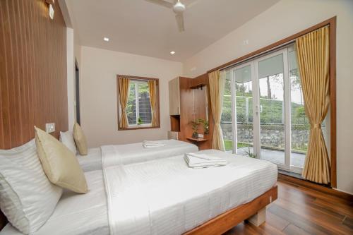 a bedroom with a large bed and a large window at Abhinav Nest by Xplore Indo in Kodanād
