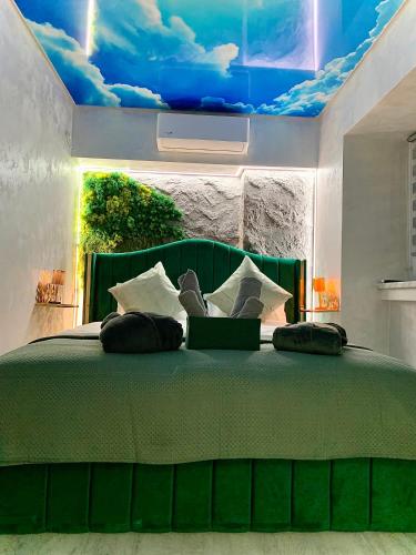 a bedroom with a green bed with a painting of clouds at Golden Station Ultraconfort in Iaşi