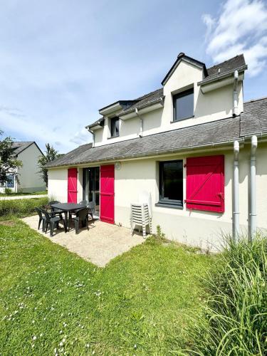 une maison blanche avec des portes rouges et une table de pique-nique dans l'établissement Maisonnette tout confort - Golf - Piscine, à Quéven