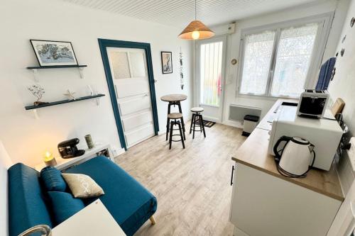 un salon avec un canapé bleu et une cuisine dans l'établissement Maisonnette tout confort proche plages et bourg, à Port-Louis