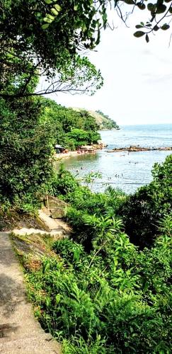a path next to a body of water with trees at Pousada Caraguatatuba in Caraguatatuba