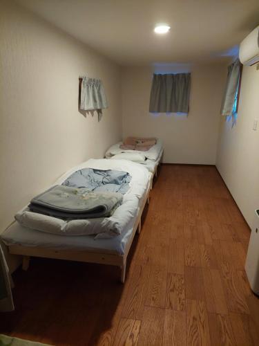 小谷村にあるペンションシルバーファーンの木製の床の部屋にベッドが2つあります