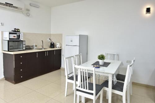 a kitchen with a white table and a white refrigerator at אחוזת איריס הגליל - וילה וסוויטות מושלמות עם בריכה מחוממת in Migdal